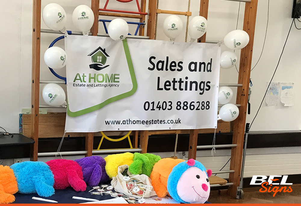 At Home Estate Agent's printed banner at an indoor event